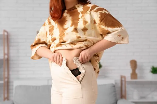 Image of woman trying to do her trousers up after pregnancy weight gain Hucknall under Huthwaite