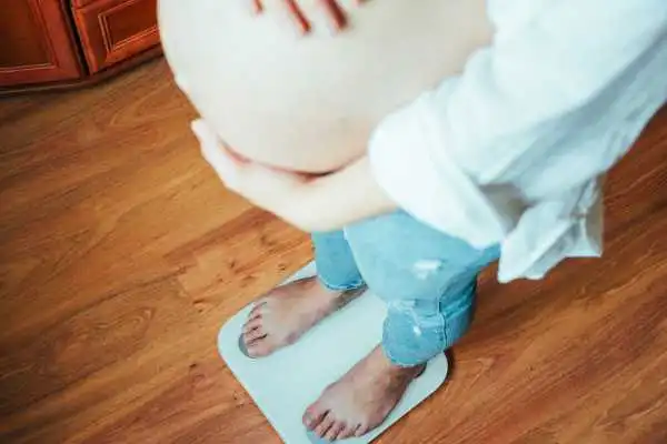 Image of woman weighing herself and experiencing weight gain through pregnancy Hucknall under Huthwaite